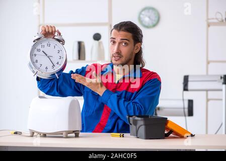 The young male contractor repairing toaster at workshop Stock Photo