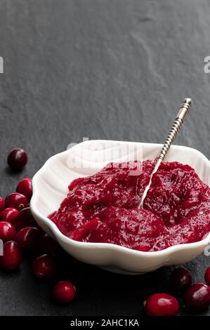 Fresh  homemade cranberry sauce in white bowl on black stone table Stock Photo