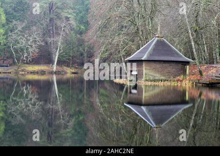 Loch Dunmore near Pitlochry in Perthshire, Scotland. Boathouse and trees reflected perfectly in calm waters of the loch. Taken in winter.