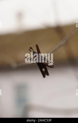 Two old wooden clothespins hanging on a clothesline Stock Photo