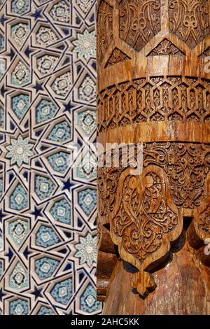 Detail own an elaborately carved wooden pillar with traditional blue glazed tiles in Tashkent, Uzbekistan. Stock Photo