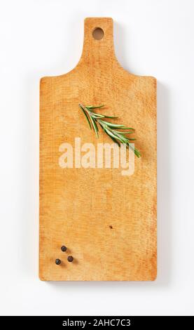 Wooden cutting board with rosemary and black peppercorns on it Stock Photo