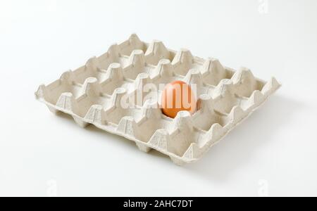 One brown egg left in a twenty dimpled egg tray Stock Photo