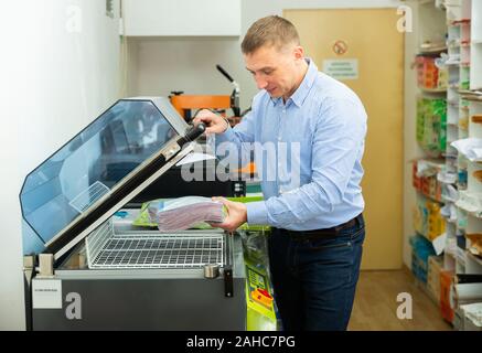 Worker packs notebooks in a vacuum packing Stock Photo
