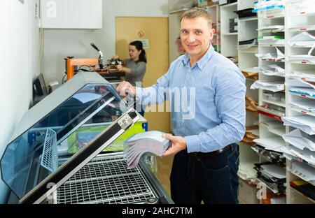 Worker packs notebooks in a vacuum packing Stock Photo