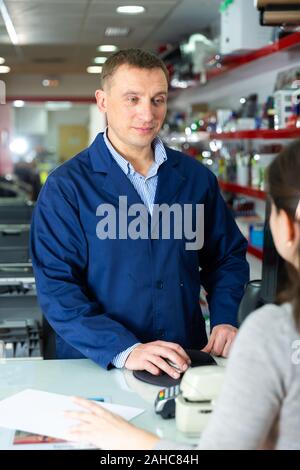 Positive administrator of the printing house gives finished product to the buyer Stock Photo
