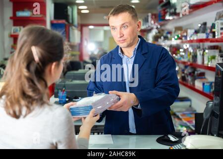 Positive administrator of the printing house gives finished product to the buyer Stock Photo