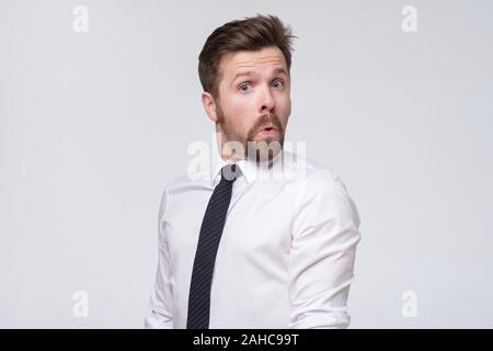 man in white shirt and tie standing and looking at camera with big eyes and unbelievable face Stock Photo
