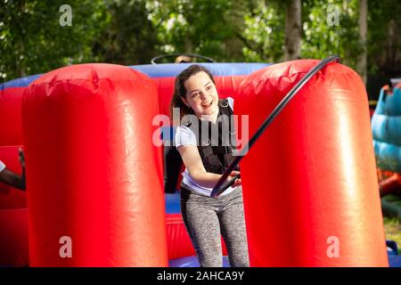 Portrait of emotional young woman putting hoop on inflatable pole during competition in outdoor amusement park Stock Photo