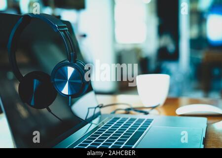 Headphones on laptop with coffee cup and mouses in blur background. Stock Photo