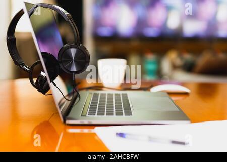 Headphones on laptop with coffee cup and mouses in blur background. Stock Photo