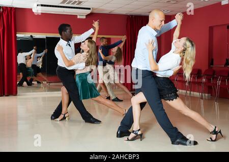 Young smiling people practicing passionate samba in dance class Stock Photo