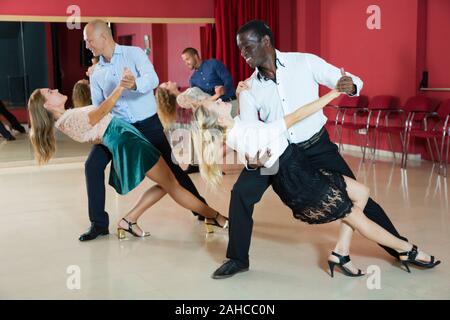 Young smiling people practicing passionate samba in dance class Stock Photo