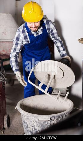 Young smiling man using concrete mixer for construction work at workplace Stock Photo