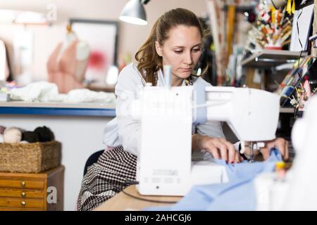 Young woman sewer working with modern sewing machine at workshop Stock Photo