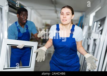 Two masters are conflicting in time working with window frame in the window workshop. Stock Photo