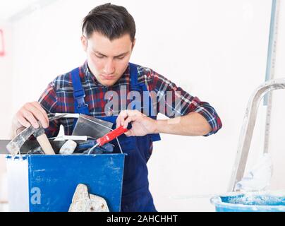 Handyman searching in his toolbox for necessary tools Stock Photo
