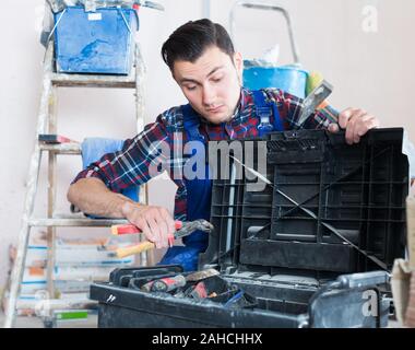 Worker repairing room and looking for necessary tool in toolbox Stock Photo