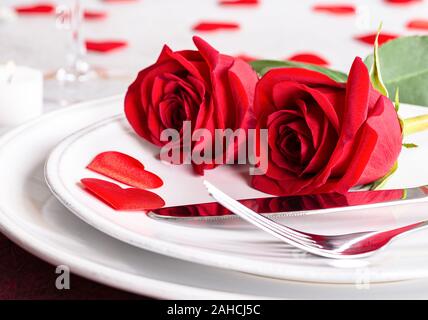Closeup of Two Red Roses on a table setting for Valentines Day Stock Photo