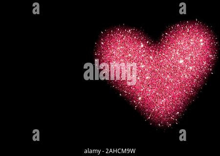 abstract background with pink heart isolated on black, shiny heart with glitter effect Stock Photo