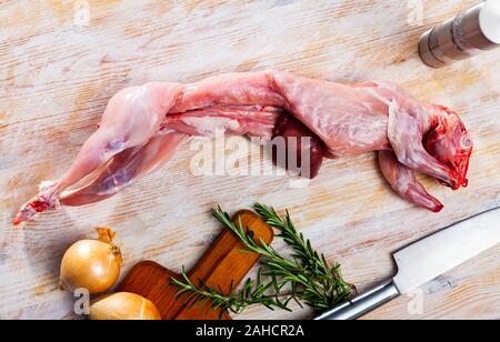 Fresh raw farmer rabbit, rosemary, onion and black pepper on light wooden surface Stock Photo