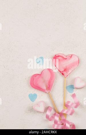 two pink hearts as lollipop candy bound pink ribbon with blue hearts around on white background. Valentines day minimalist background. love symbol, sp Stock Photo