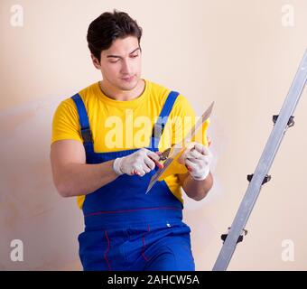The young contractor employee applying plaster on wall Stock Photo