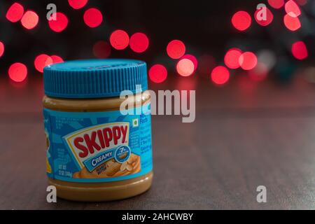 Minneapolis, Minnesota - December 23, 2019: Skippy brand peanut butter sitting on a table, red bokeh balls in the background Stock Photo