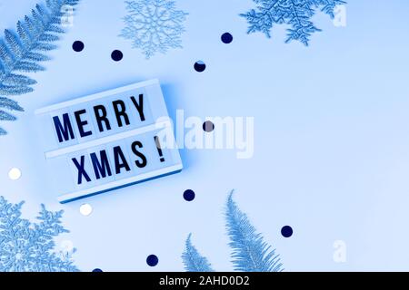 Merry xmas words on light box with snowflakes, tree branches . xmas and new year card top view flat lay close up copy space color of the year 2020 Stock Photo