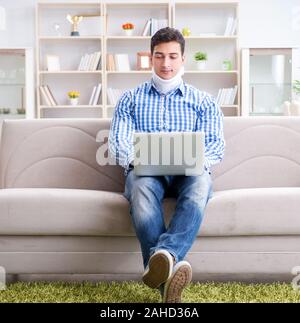 The man freelancer in a cervical collar neck brace working from home Stock Photo
