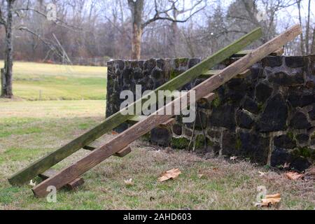 The ladder is leaning against the stone wall. Stock Photo