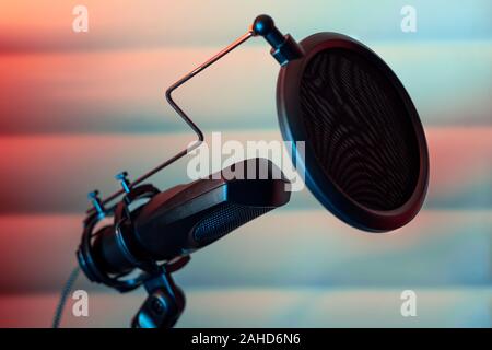 Condenser microphone placed on a tripod with acustic panels in the  background in a music studio, ready for recording. Stock Photo