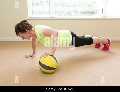 woman doing push ups using medicine exercise ball Stock Photo