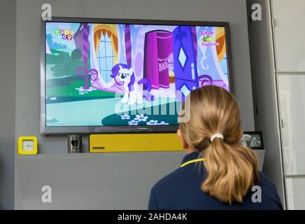 young girl watching cartoons on television Stock Photo