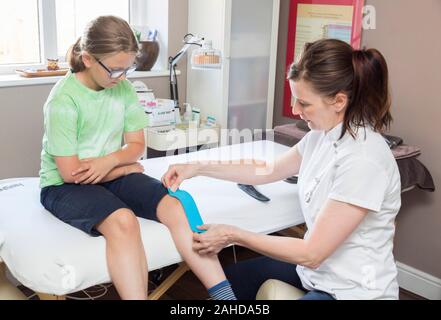 therapist applying kinesio tape to young girl Stock Photo