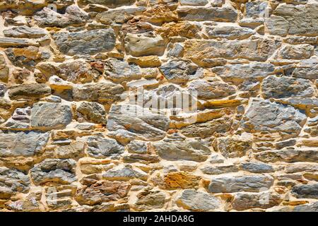 Surface with asymmetrical stones. Wall pattern texture background. Old wall of ancient architecture. Rome, greek culture, architecture. Fragment of historic building Pattern, sample for designers Stock Photo