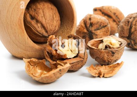 Group of walnut grains and whole walnuts with nutcracker on a white background in close-up Stock Photo