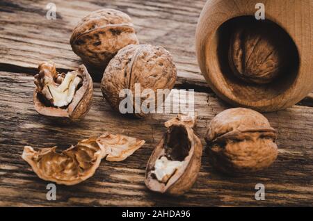 Group of walnut grains and whole walnuts with nutcracker on a wooden rustic table (vintage effect) Stock Photo