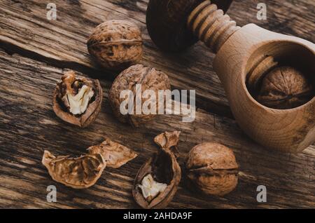 Group of walnut grains and whole walnuts with nutcracker on a wooden rustic table (vintage effect) Stock Photo