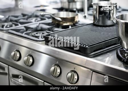 Part of a modern kitchen in the restaurant or hotel with professional equipments - steel gas cooker, pots and pans ( low DOF) Stock Photo