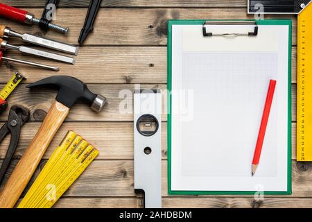 Top view to the carpenter's tools and notebook for notes on an antique wooden table. Construction industry, do it yourself. Wooden work table. Stock Photo