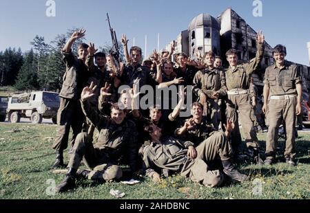 13th August 1993 During the war in Bosnia: victorious BSA (Bosnian-Serb) soldiers give the 'Serb salute' as they pose in front of the burned-out Hotel Famos (today called the Hotel Maršal) on Bjelašnica mountain. Stock Photo
