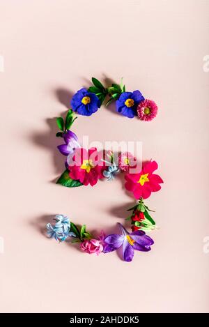 Easter minimal concept. Letter S made from spring flowers on the pink background Stock Photo