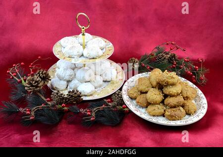 Greek traditional Christmas desserts, kourabiedes and melomakarona, decorated with Christmas tree branches on red background Stock Photo