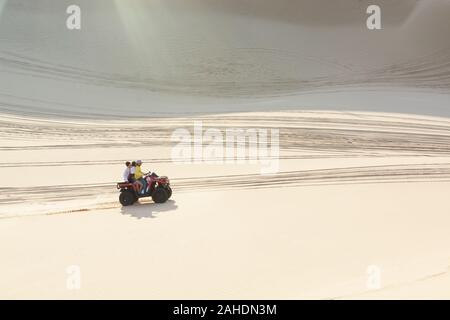 Mui Ne, Vietnam - June 2019: off-road ATV quad bike driving through desert sand dunes at sunrise. Stock Photo