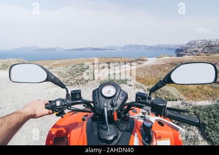 ATV quad bike driving along the shore of Aegean sea on Santorini island, Greece. View from driver seat Stock Photo