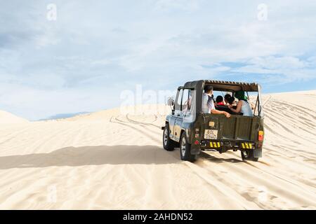 Mui Ne, Vietnam - June 2019: off-road vintage soviet car driving through desert sand dunes at sunrise. Stock Photo