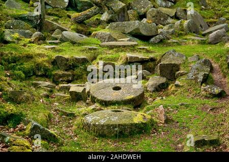 Abandoned completed millstones stacked at a small quarry in Lawrence Field above Padley Gorge near Grindleford, Peak District Stock Photo