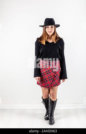 Studio shoot of beautiful lady in red plaid skirt and black knitted sweater. Model fashion shooting. Autumn, winter season. Stock Photo