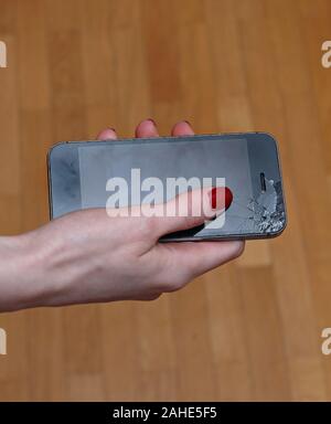 Female hand holding dropped smart phone with broken screen Stock Photo